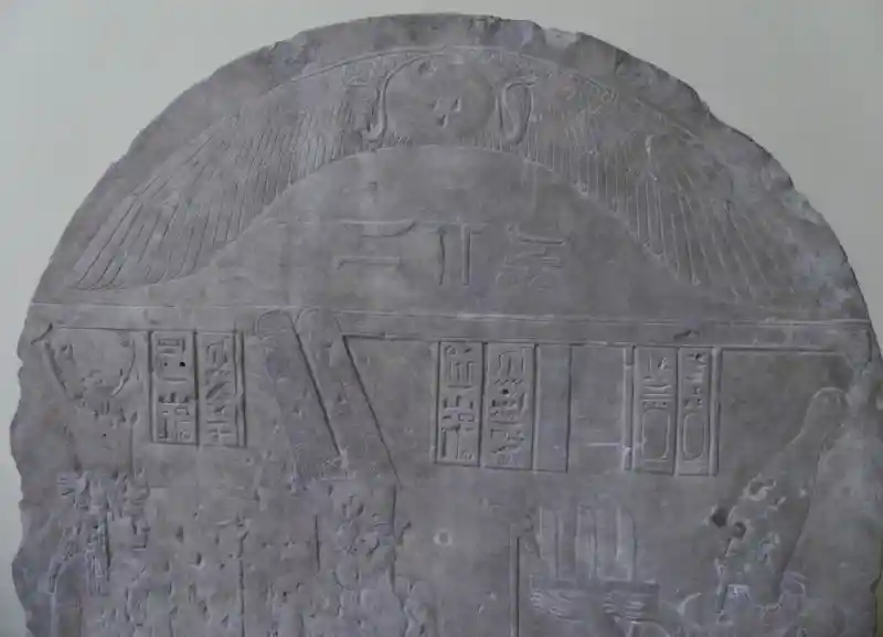 A disc, with snakes and very long wings on the sides engraved on a relief stele